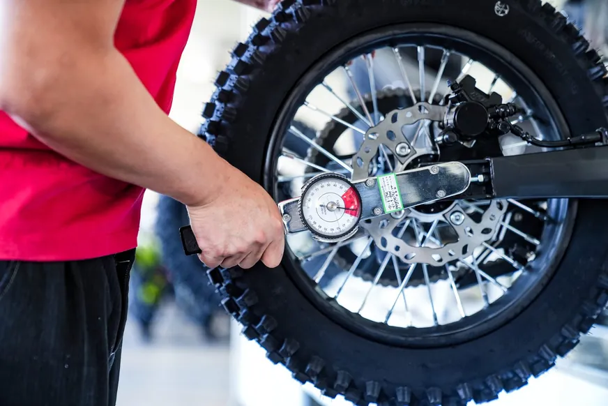 A digital torque wrench being used on a rear axle, with the torque value recorded